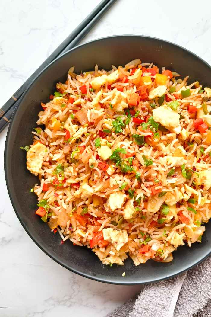 vegetable fried rice in a black ceramic plate