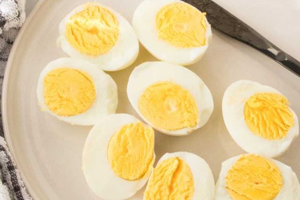 Air fryer hard boiled eggs in a ceramic plate with a black butter knife