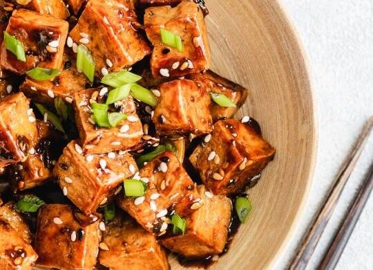 teriyaki tofu in a wodden bowl with chopsticks magenta streaks