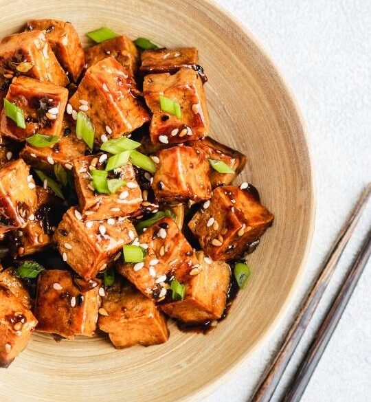 teriyaki tofu in a wodden bowl with chopsticks magenta streaks