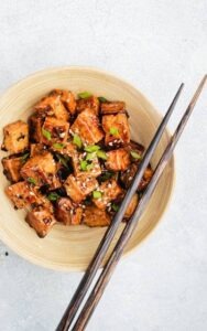 vegan teriyaki tofu in a wodden bowl with chopsticks