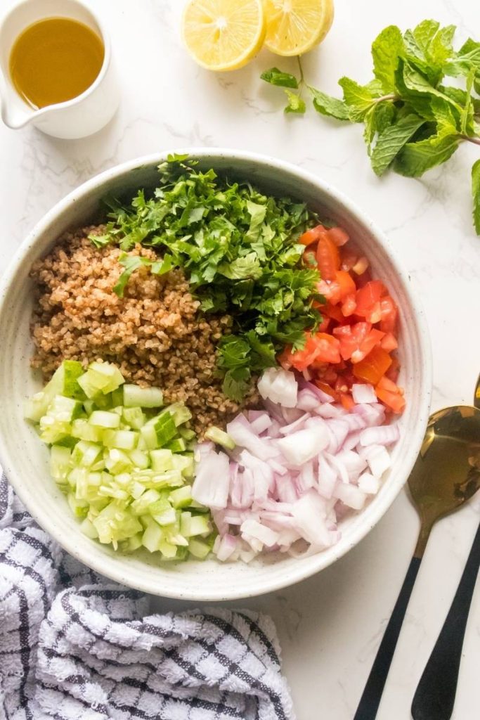 all chopped quinoa salald ingredients in a large serving bowl with salald dressing and lemon slices