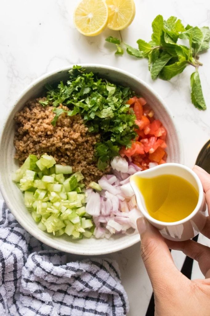 pouring salald dressing to quinoa tabbouleh salad