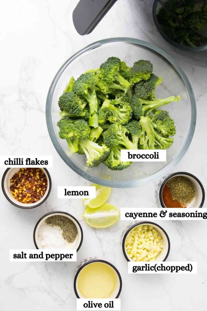 Ingredients measured out to make air fryer broccoli garlic powder, salt, pepper, olive oil and lemon, broccoli