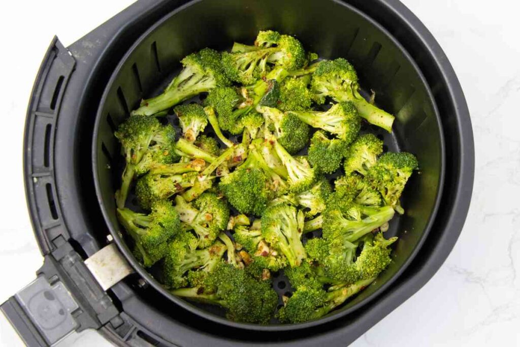 seasoned raw broccoli in an air fryer