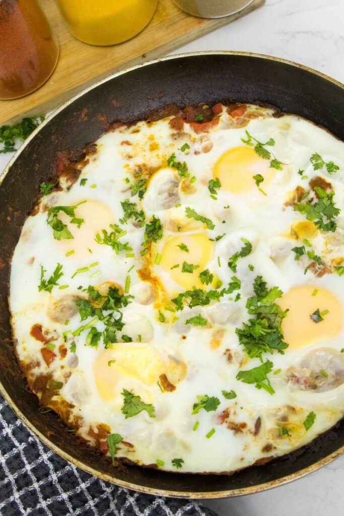 This image shows a savory Middle Eastern and North African breakfast dish called Shakshuka, cooked in a pan