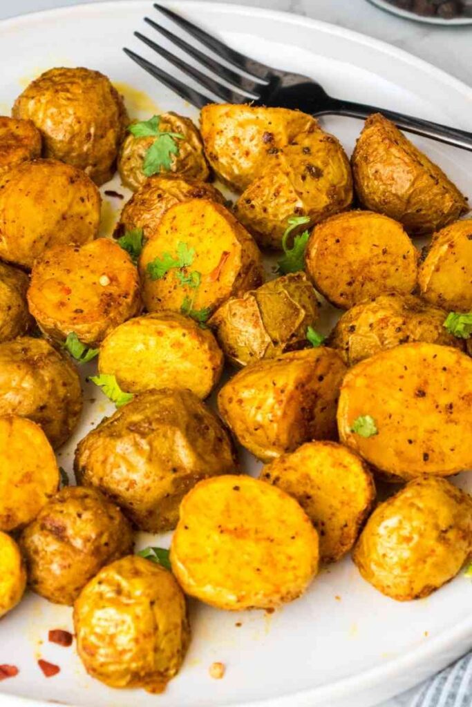 Air fryer baby potatoes on a white serving plate with black fork