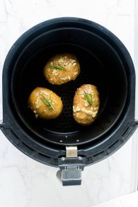 3 air fryer hasselback potatoes in black air fryer basket