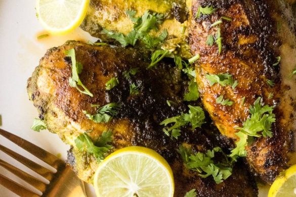 Three cooked cilantro lime chicken breasts on a white plate with a black spoon