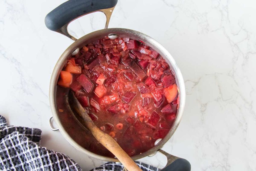 Large pot filled with vegetable broth and ingredients to make the vegan beet soup