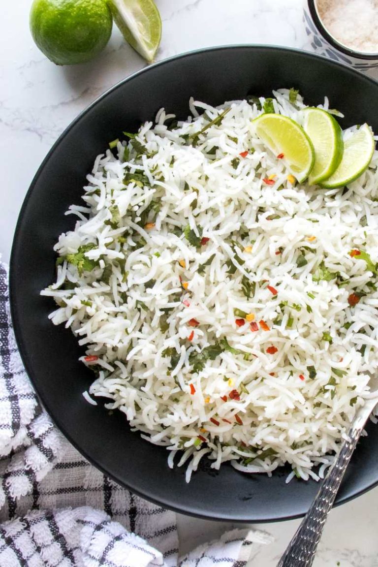 black bowl filled with cilantro lime rice, garnished with red chili flakes, and topped with lemon wedges