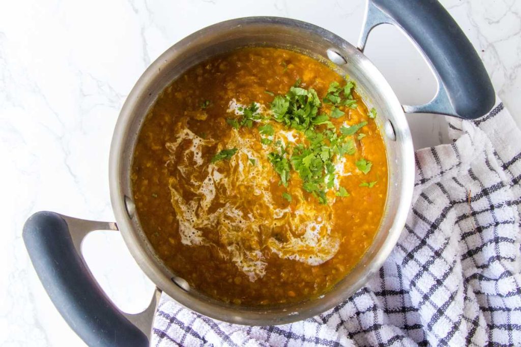 large pot filled with red lentil soup garnished wiht fresh cilantro