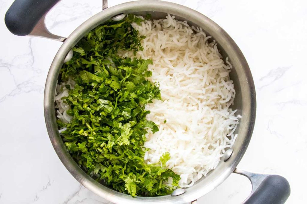 large pot filled with white rice and freshly chopped cilantro lime juice and salt