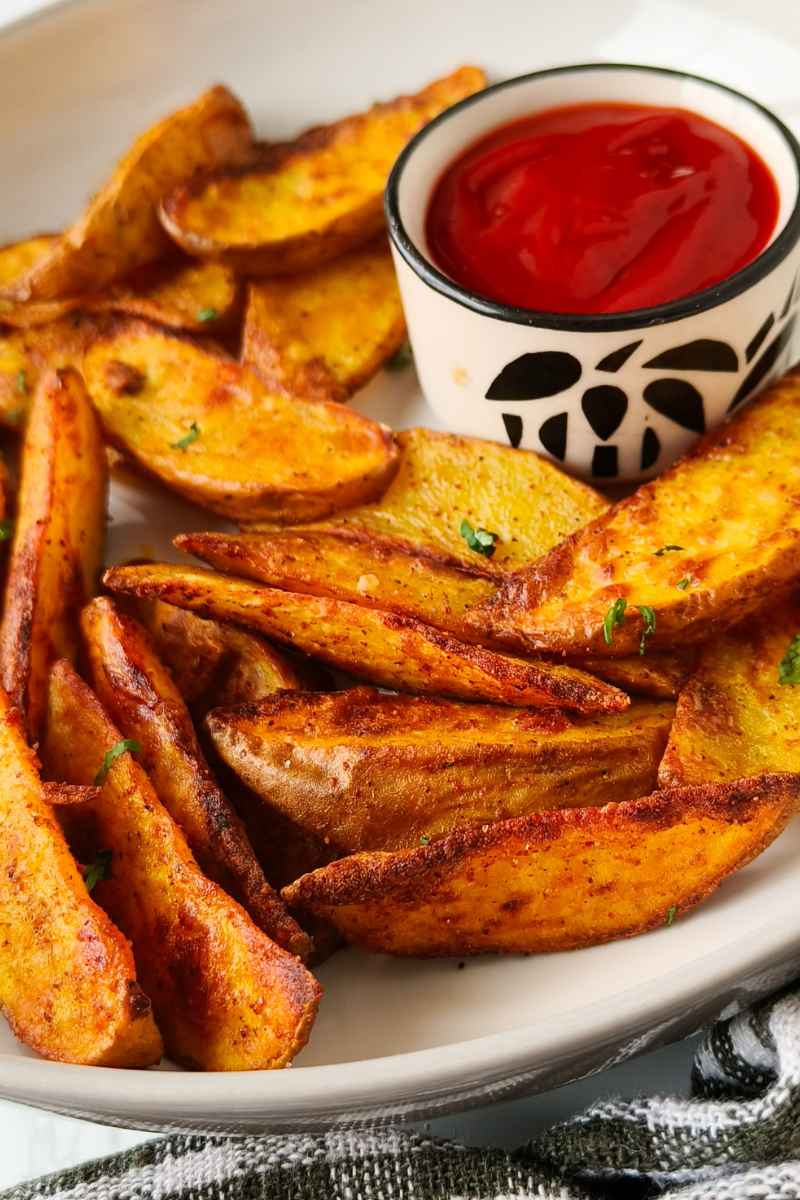 Air Fryer Potato Wedges topped with parsley along with tomato sauce