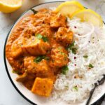 Vegan butter chicken in bowl with white rice, lemon slices