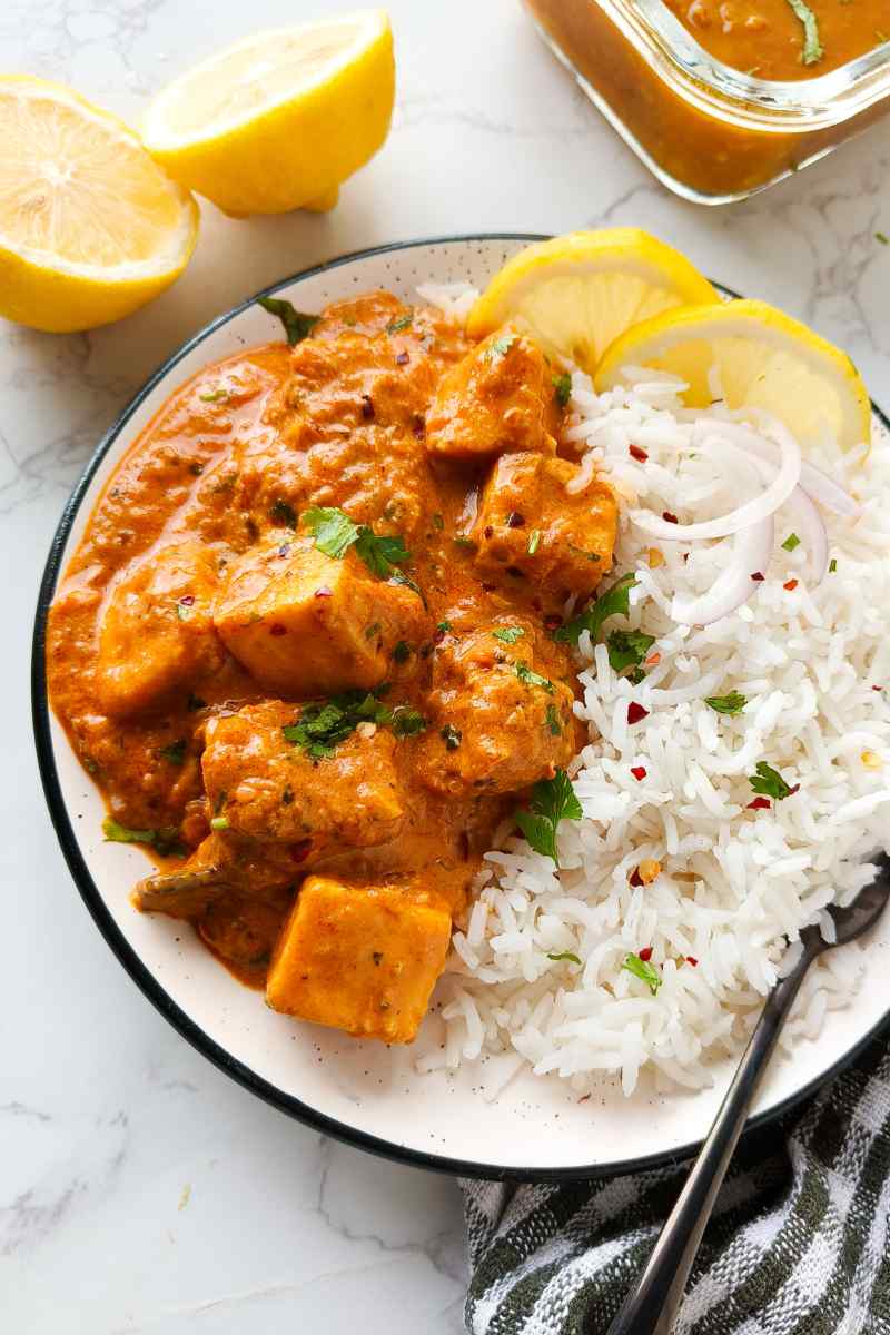 Vegan butter chicken in bowl with white rice, lemon slices