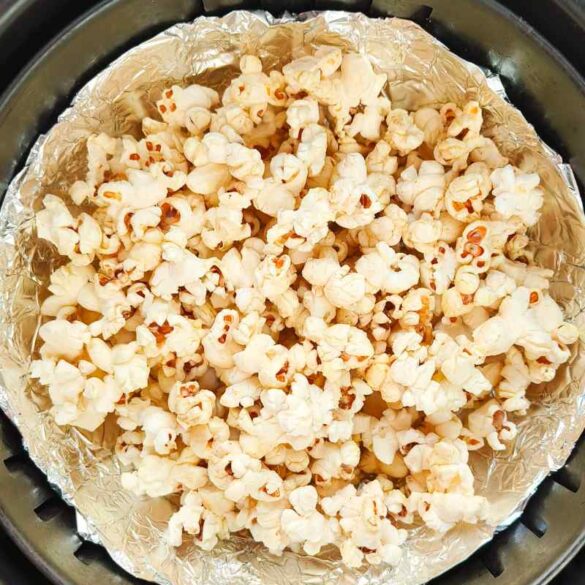 closeup of air fryer popcorn in an air fryer basket with tin foil