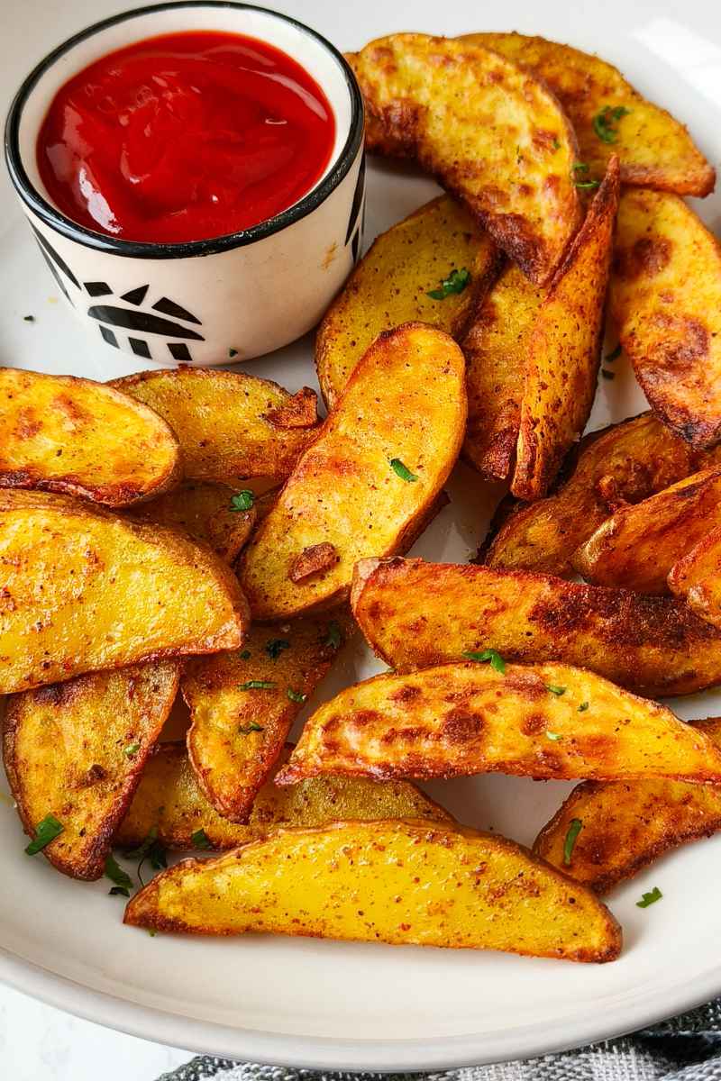 easy and quick air fryer potato wedges on a plate with red tomato sauce