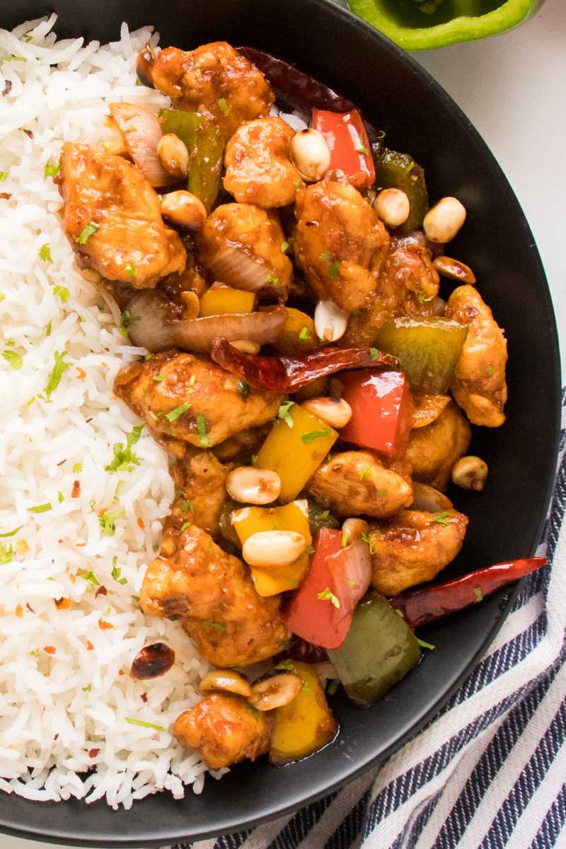 close up to kung pao chicken recipe in a black bowl served with white rice