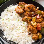 close up to kung pao chicken recipe served in a balck bowl with white rice