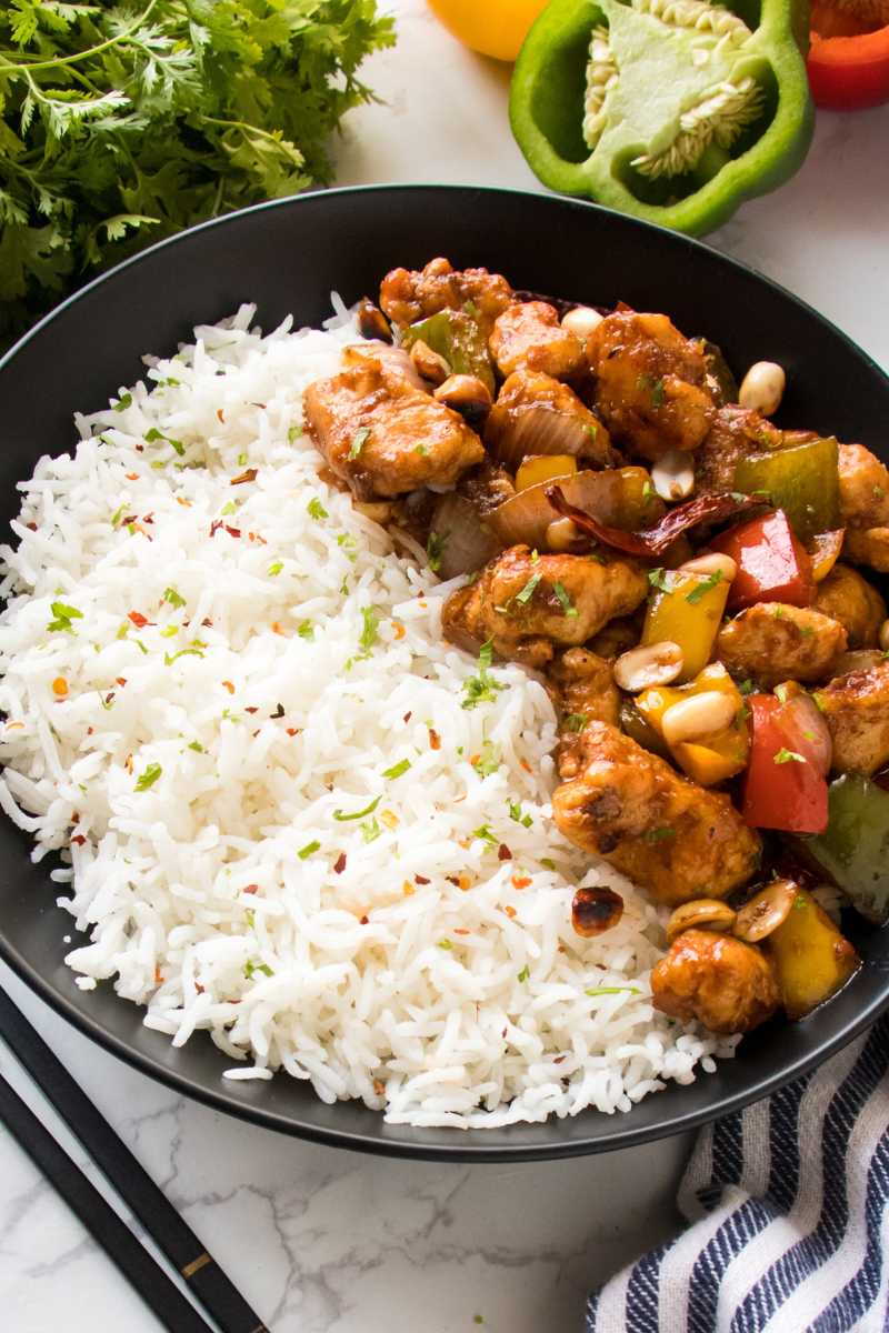 close up to kung pao chicken recipe served in a balck bowl with white rice