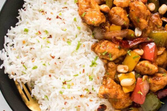 kung pao chicken recipe in a black bowl served with white rice garnished with cilantro