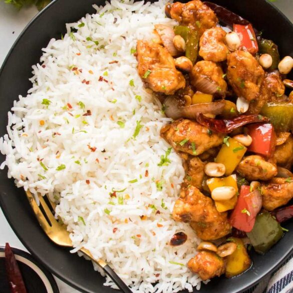 kung pao chicken recipe in a black bowl served with white rice garnished with cilantro