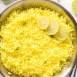 lemon rice with leom slices in stainless steel pan with cilantro and garlic cloves